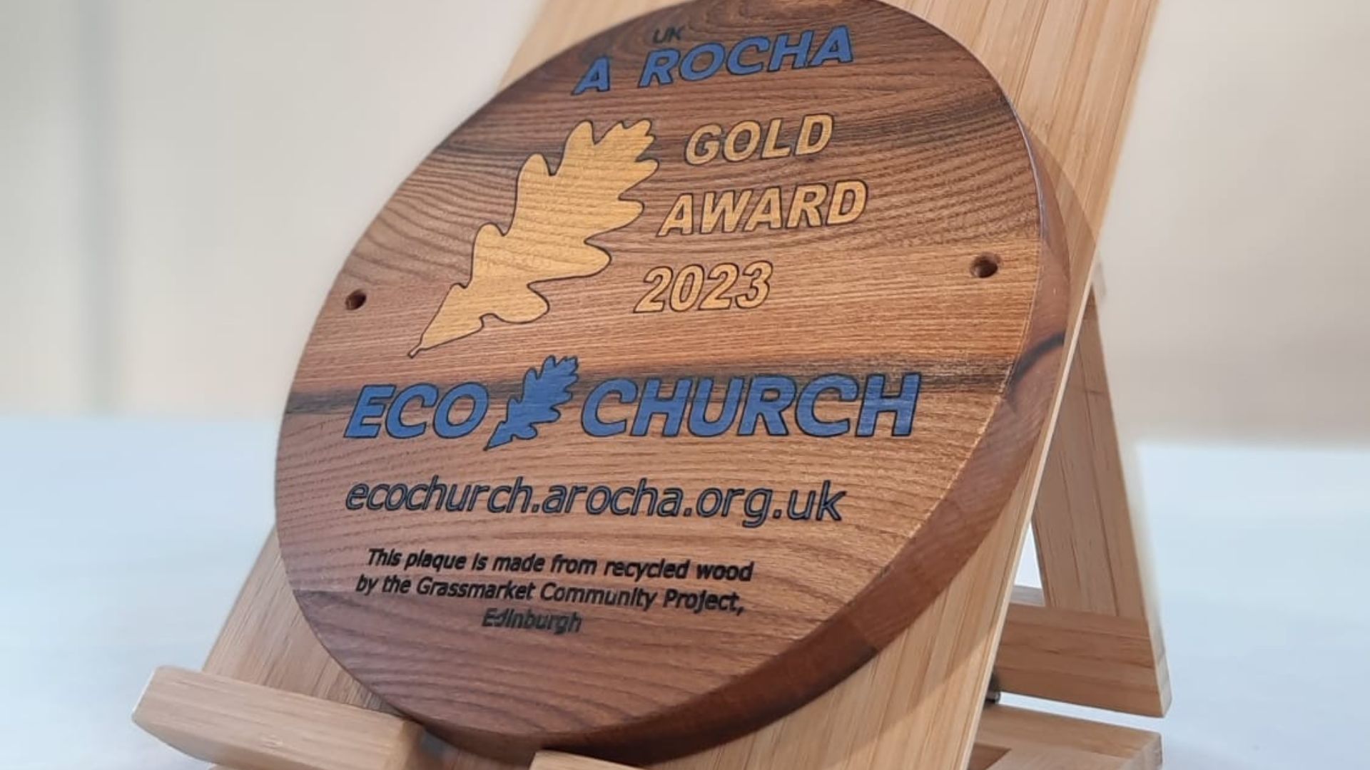 A wooden plaque stands on an altar, inscribed with the words Gold award Eco Church