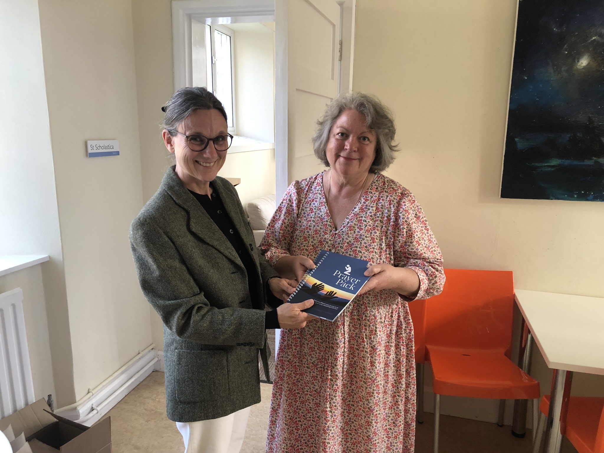 Susanne (left) offers a Prayer Pack Book to launch attendee