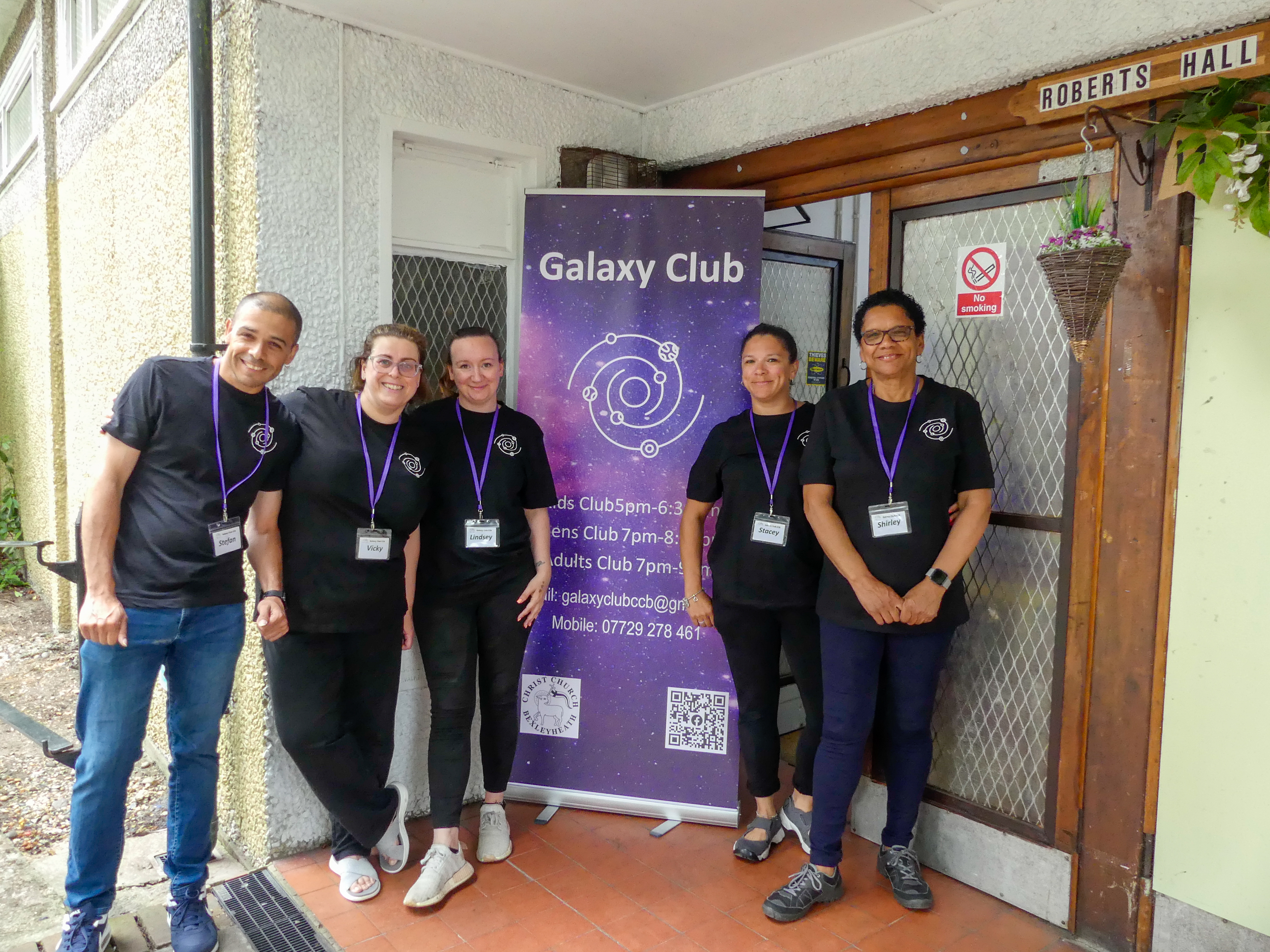 The team at Galaxy Club stand beside their group's pull up banner