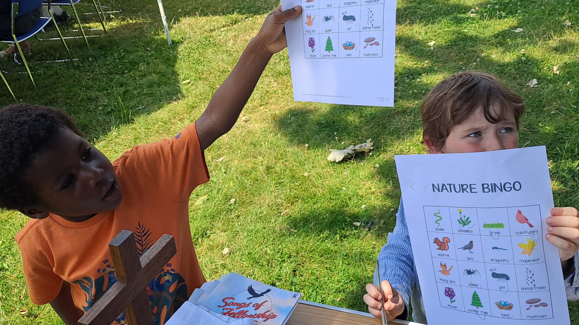 Two young boys hold up nature bingo cards