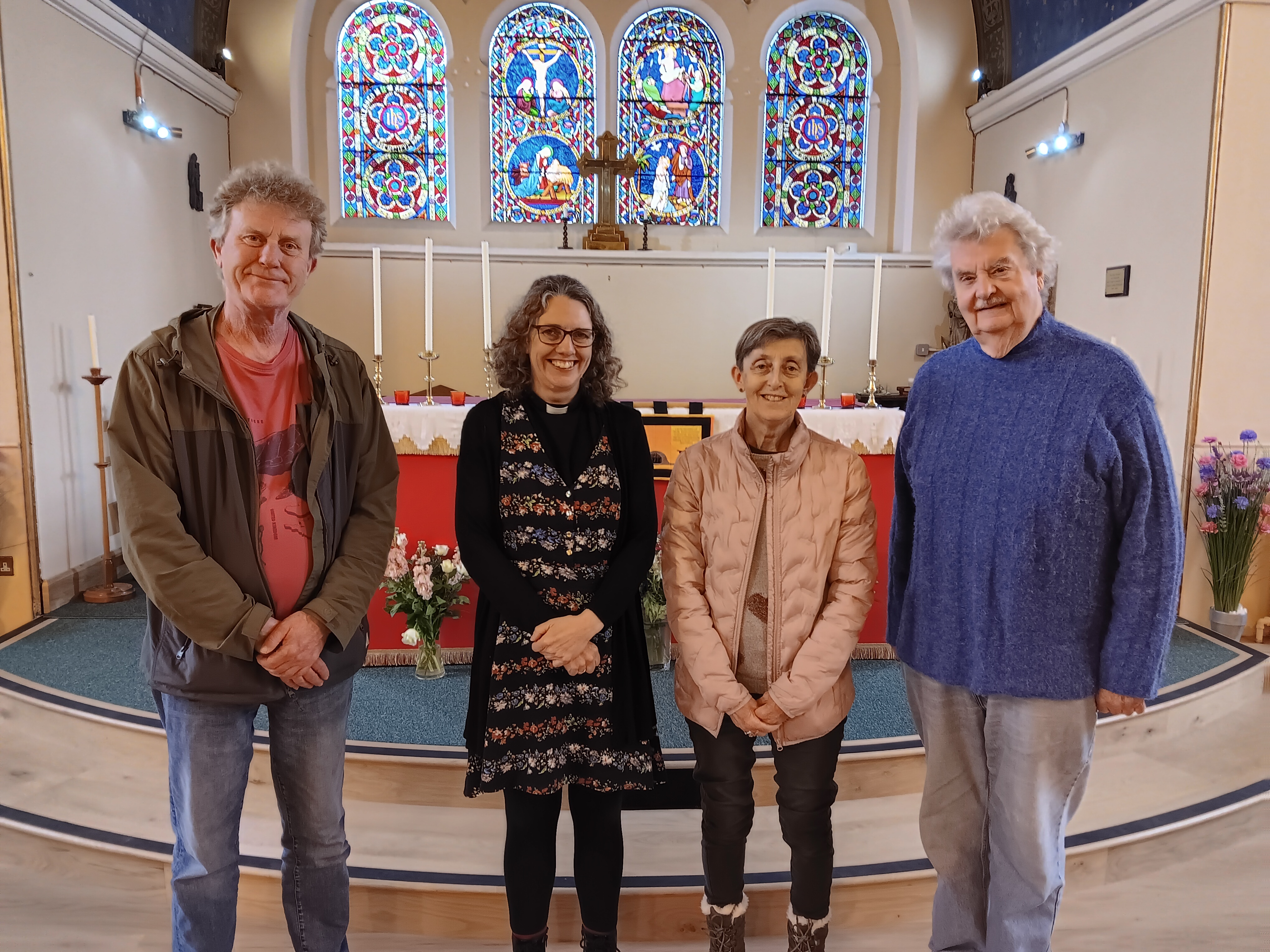 Rev Sue Vallent-Kerr (centre) stands with other members of the church team. The church's stained glass window behind them