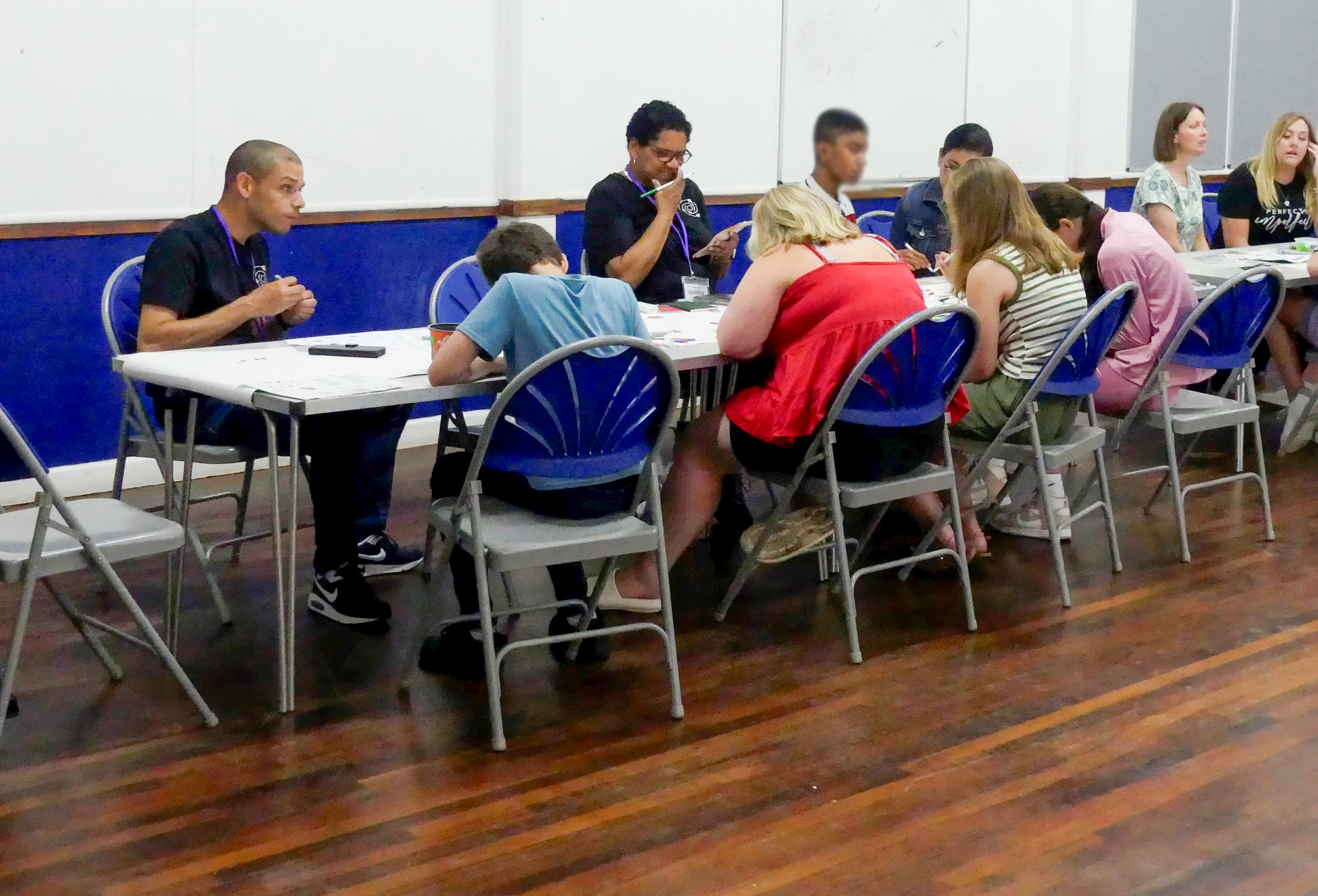 Young people and grown ups sit around a table playing bingo