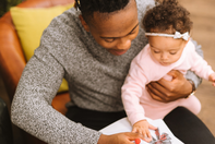 A young father and his baby girl smile as they do some crafting together