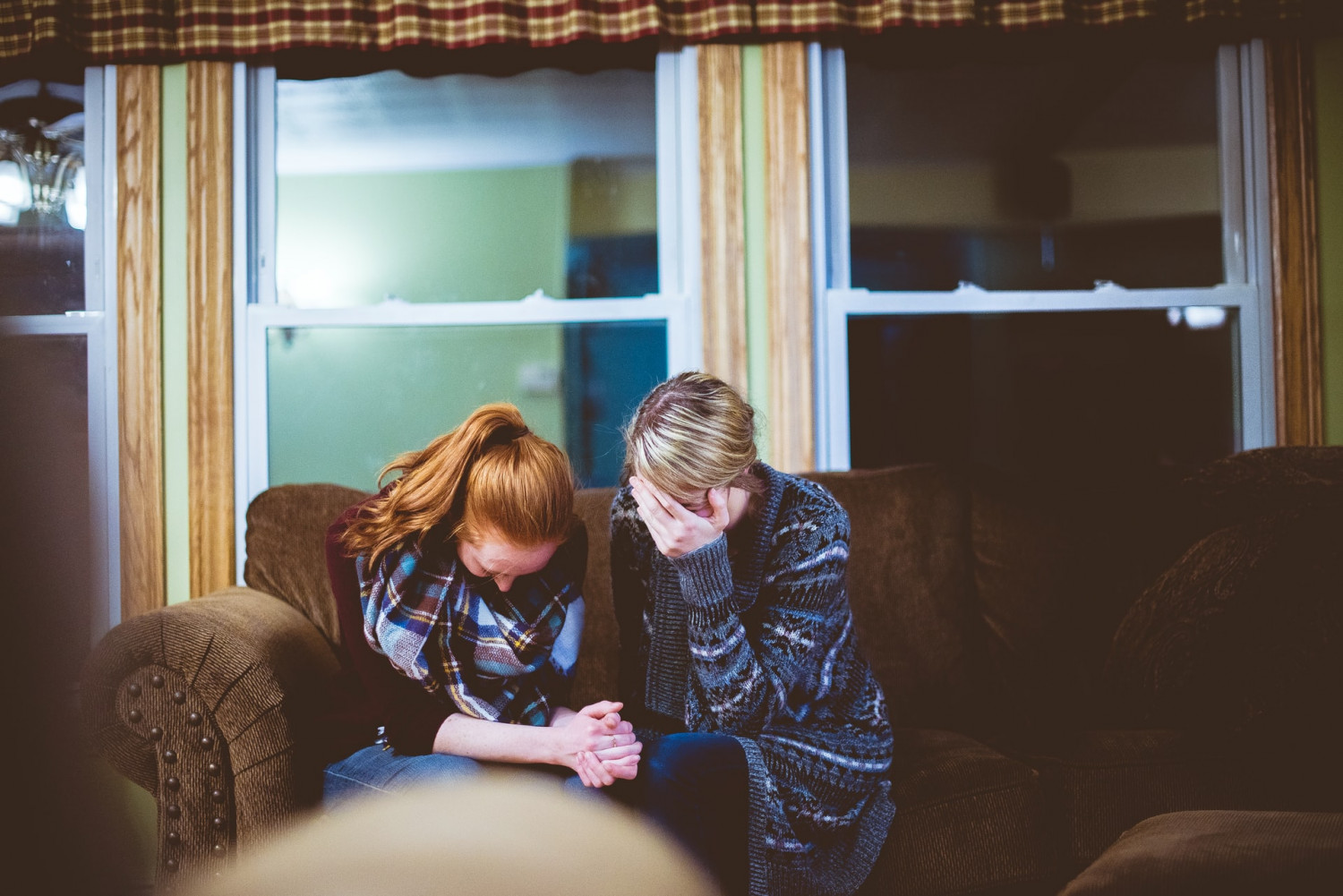 Two people comfort each other. One appears to be crying while the other holds their hand