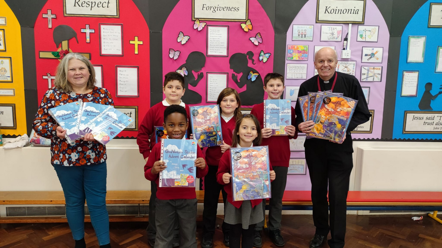 Children from St Paul's C of E Primary School line up and smile with their teacher and Vicar the Revd Jim Bennett  as they hold up their Advent Calendars