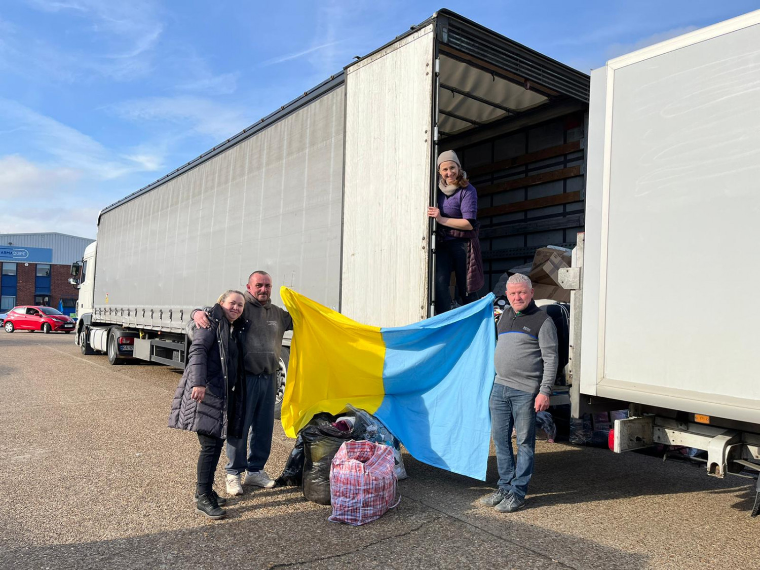 Truck being uploaded with goods as a Ukrainian flag us held up