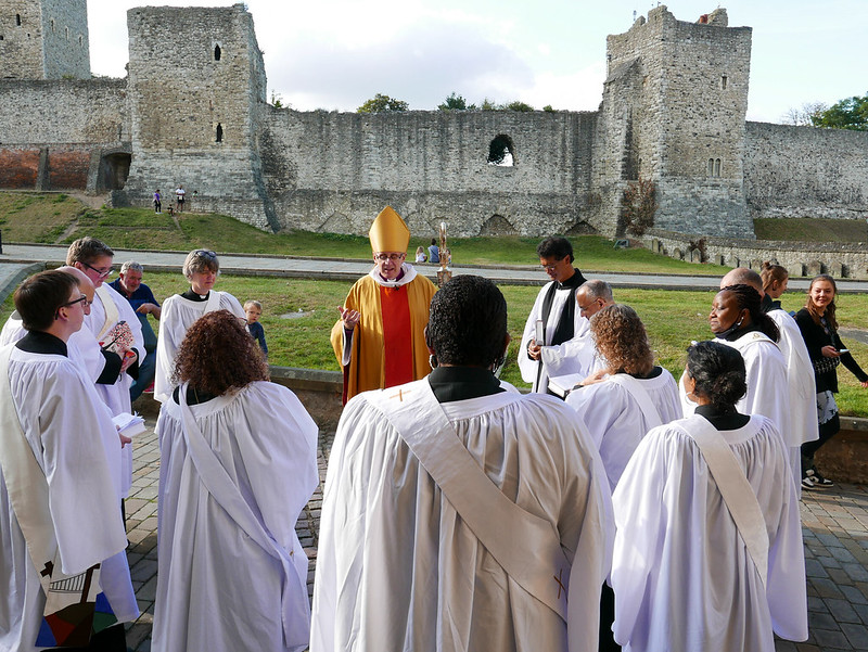 New ordinands in white robes gather around Bishop Simon as he prays for them outside Rochester Cathedral.