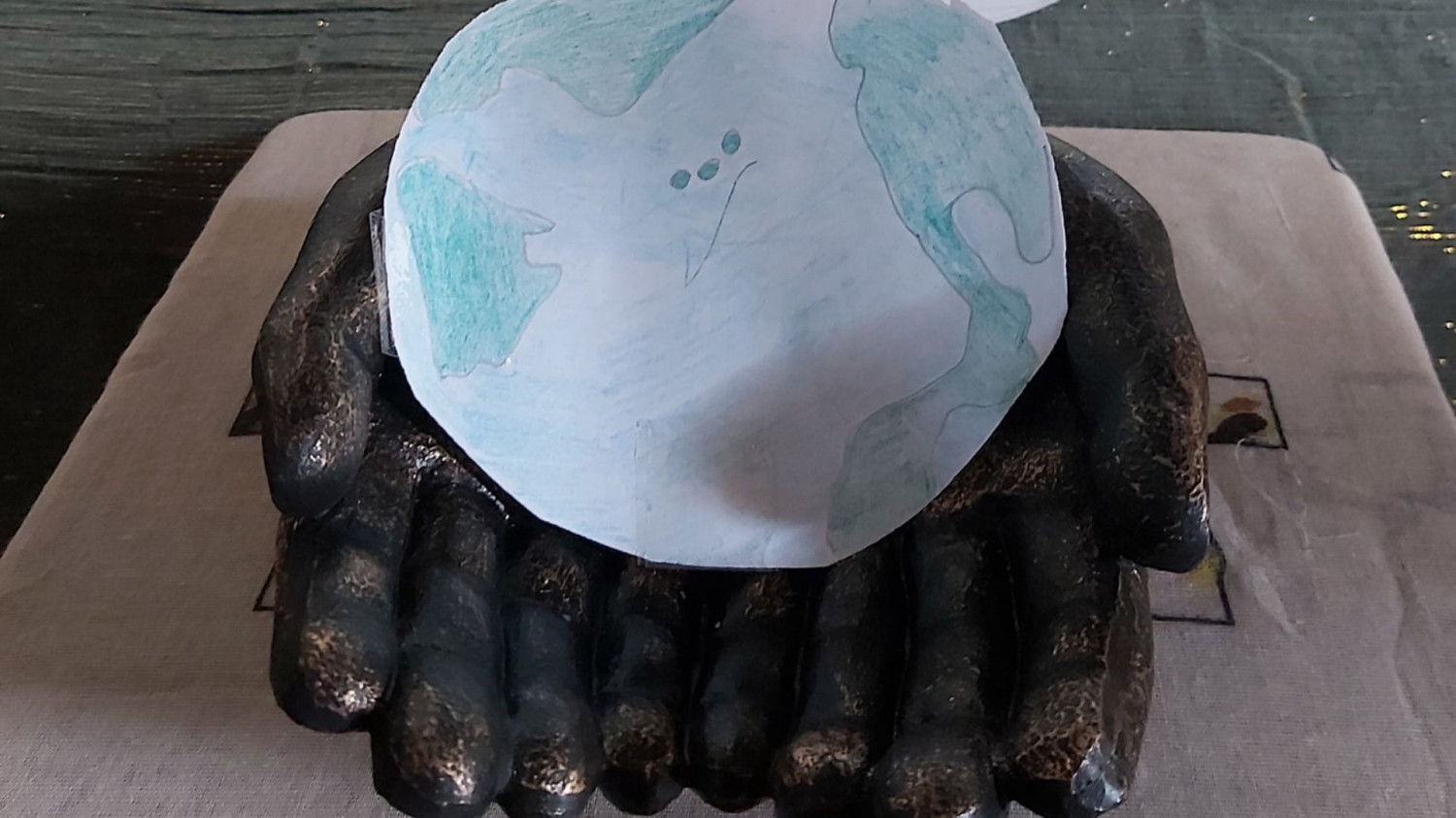 A child's picture of the earth is held in some clay hands as part of a prayer station 